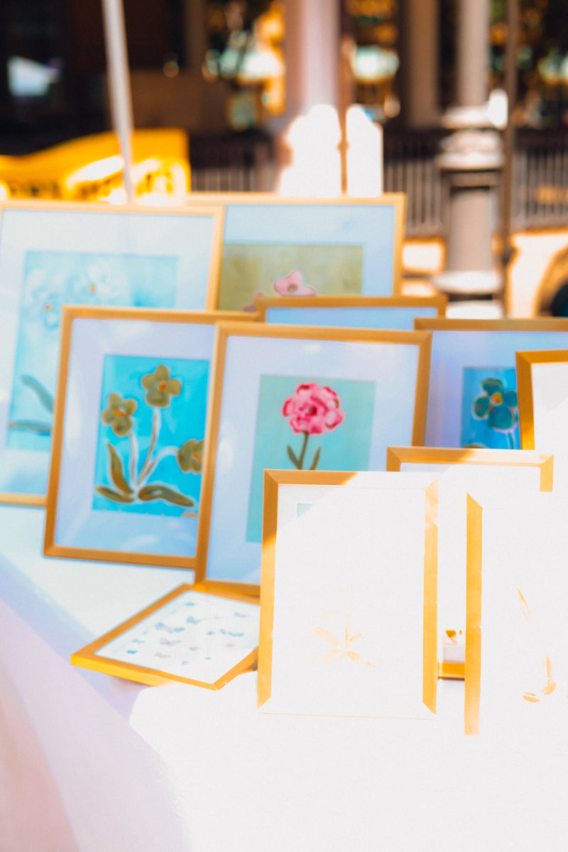 Artistic floral paintings in frames on a table with a blurred indoor background