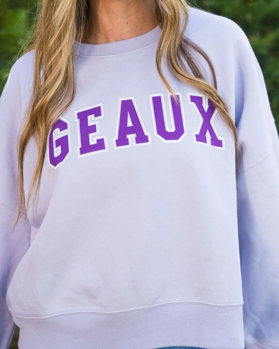 Close-up of the purple varsity GEAUX lettering on the lavender cropped sweatshirt