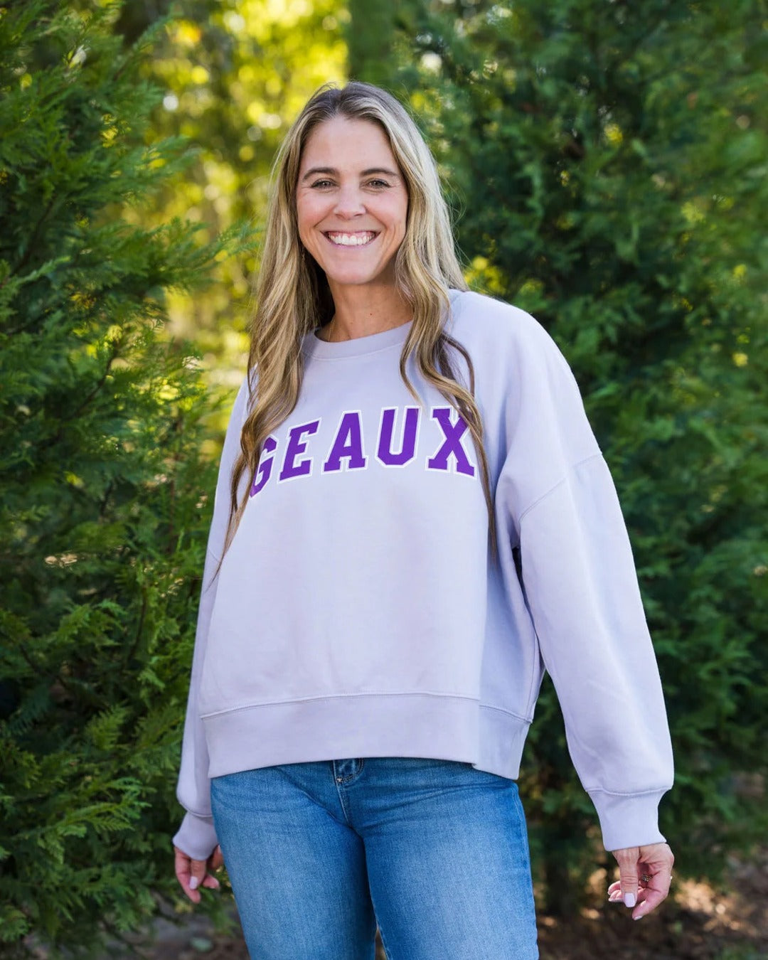 Relaxed cropped fit of the Geaux Block Sweatshirt in lavender styled with jeans