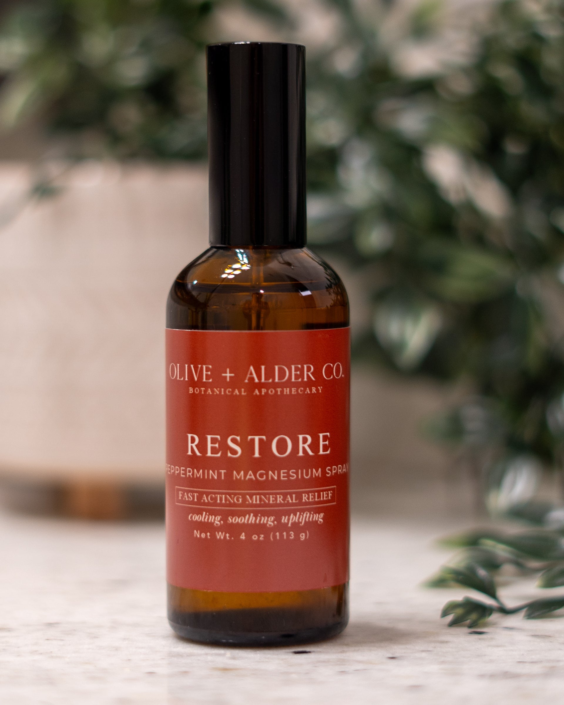 Bottle of 'Restore' supplement with a red label on a wooden surface, blurred plant in the background