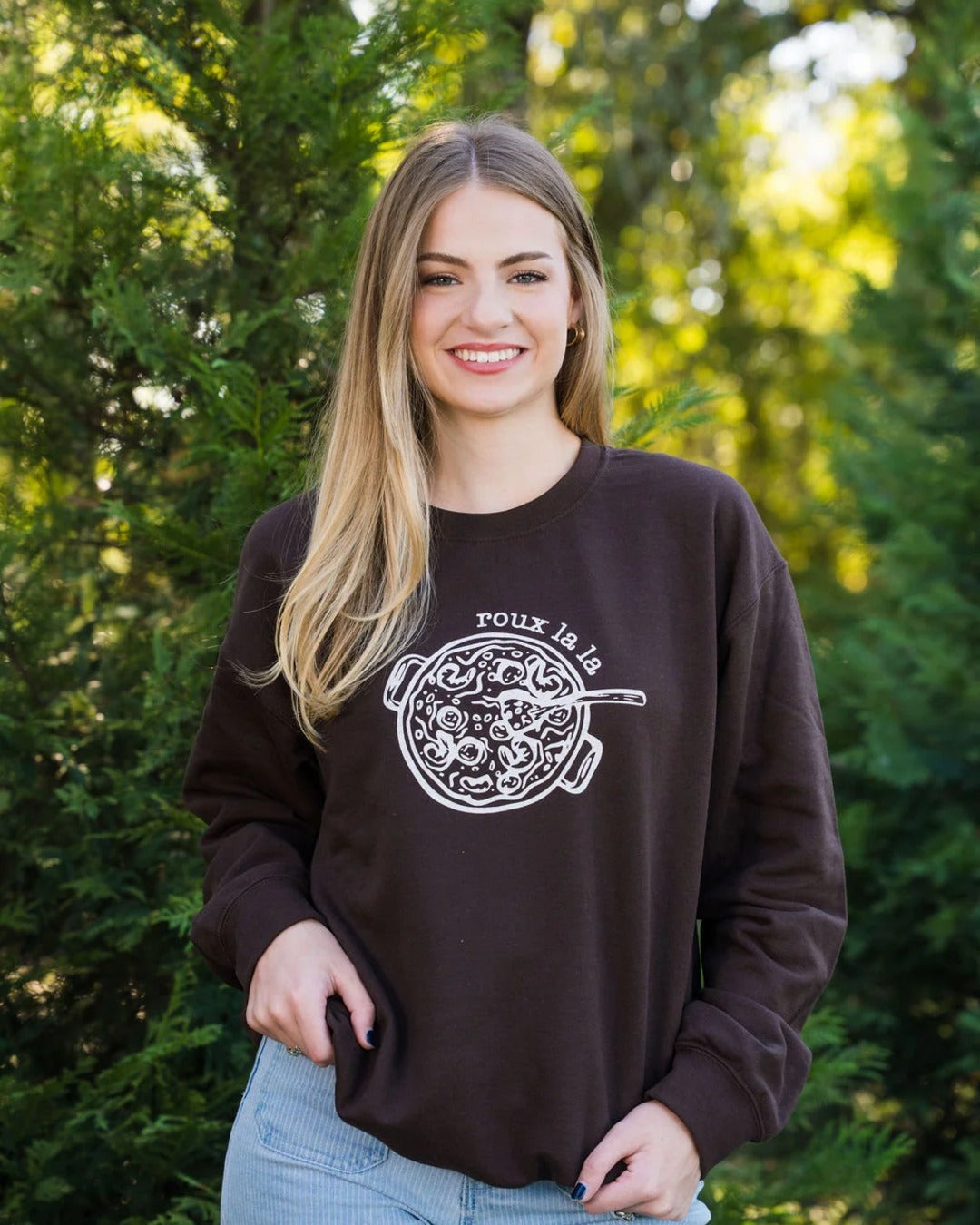 Woman wearing the Roux La La Sweatshirt in Dark Chocolate with jeans, a Louisiana gumbo sweatshirt by Sweet Baton Rouge