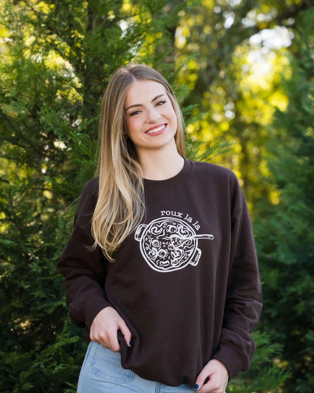 Smiling model in the Roux La La Sweatshirt, a unisex dark chocolate crewneck