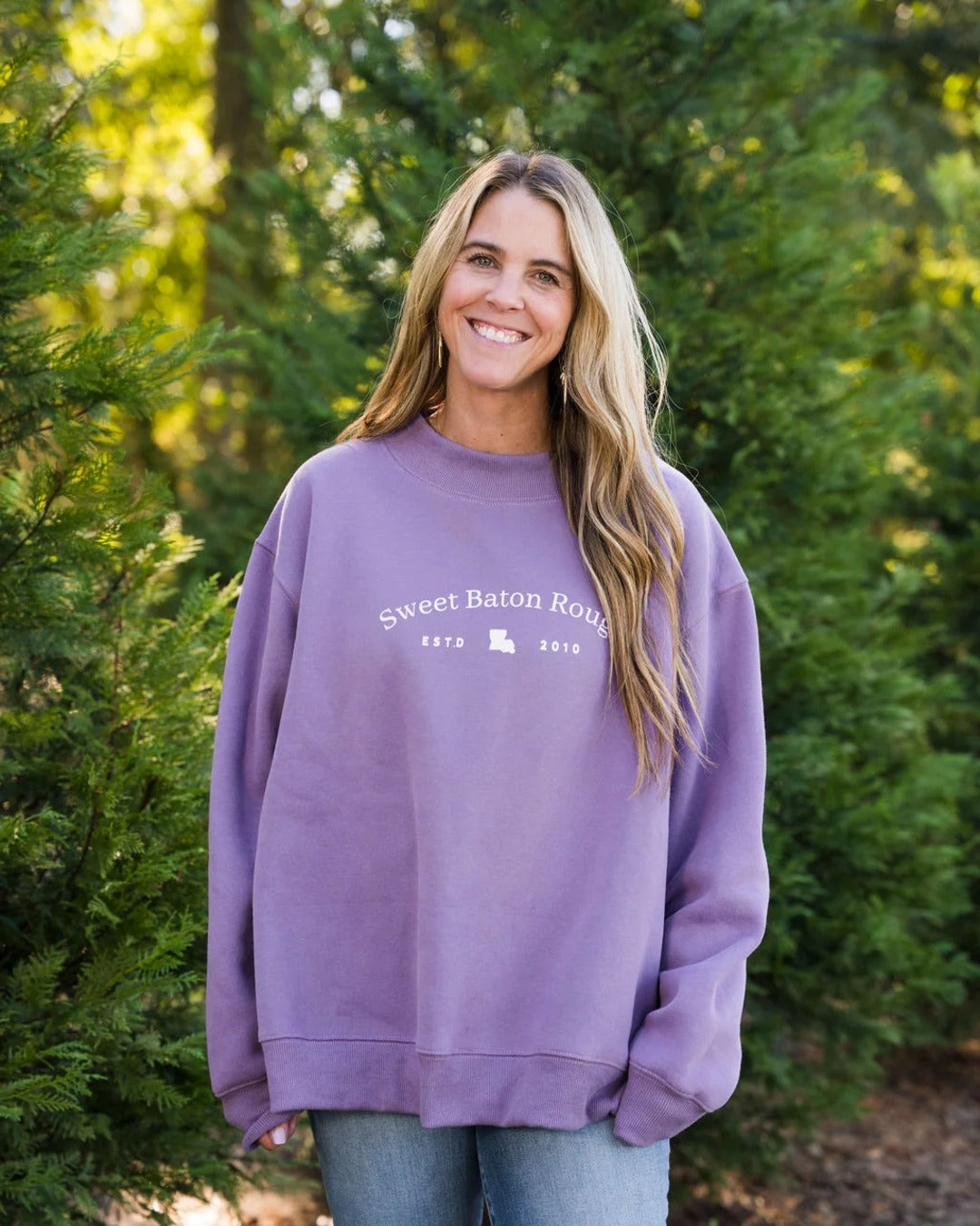 Woman wearing the Sweet Baton Rouge Travels Oversized Mock Neck Sweatshirt in lavender with jeans